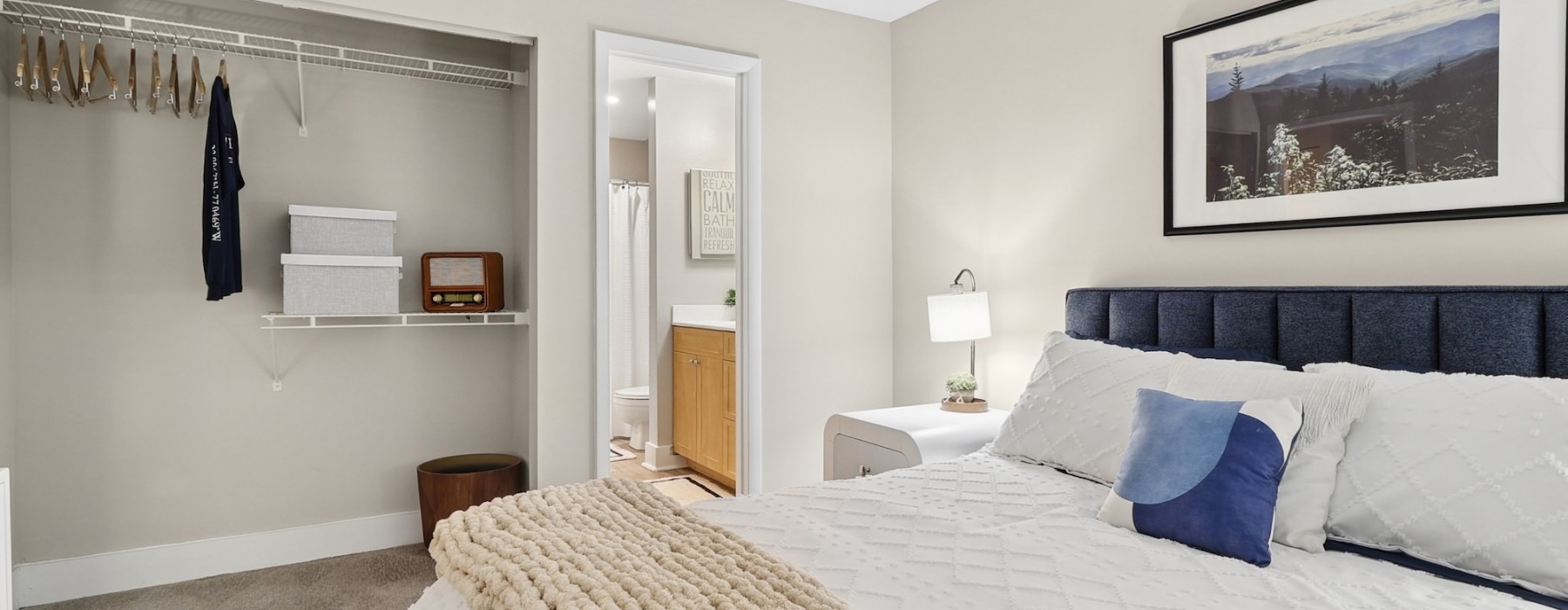 Detail of a model bedroom at Arbors on Duke Apartments in Alexandria, VA, featuring a nightstand and white bedspread.